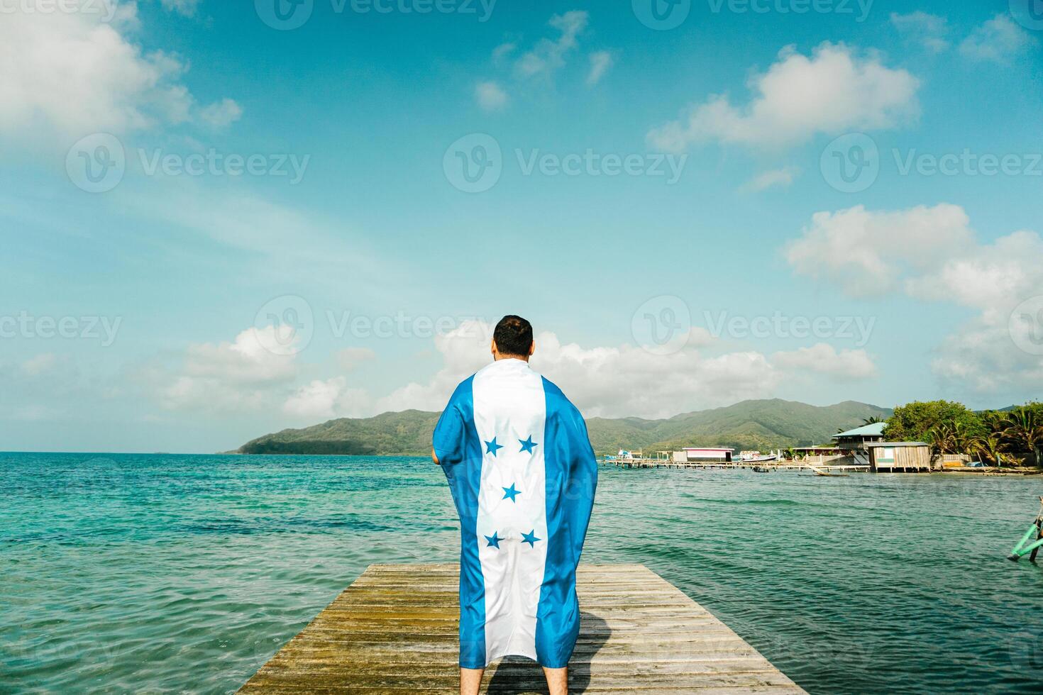 A person with honduras flag in front a sea and a island, photo