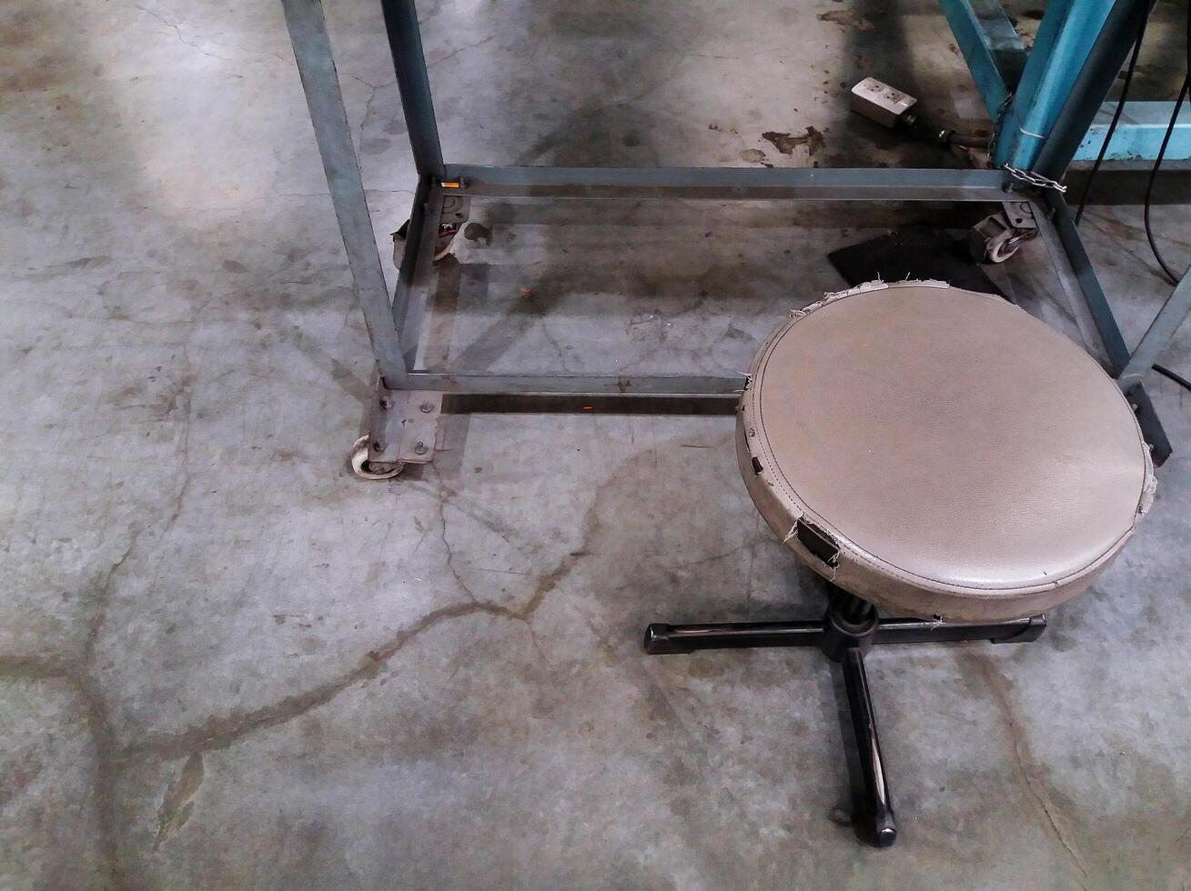 Old brown leather stool chair for sitting with stainless leg of table and AC outlet on gray or grey concrete floor with copy space. photo