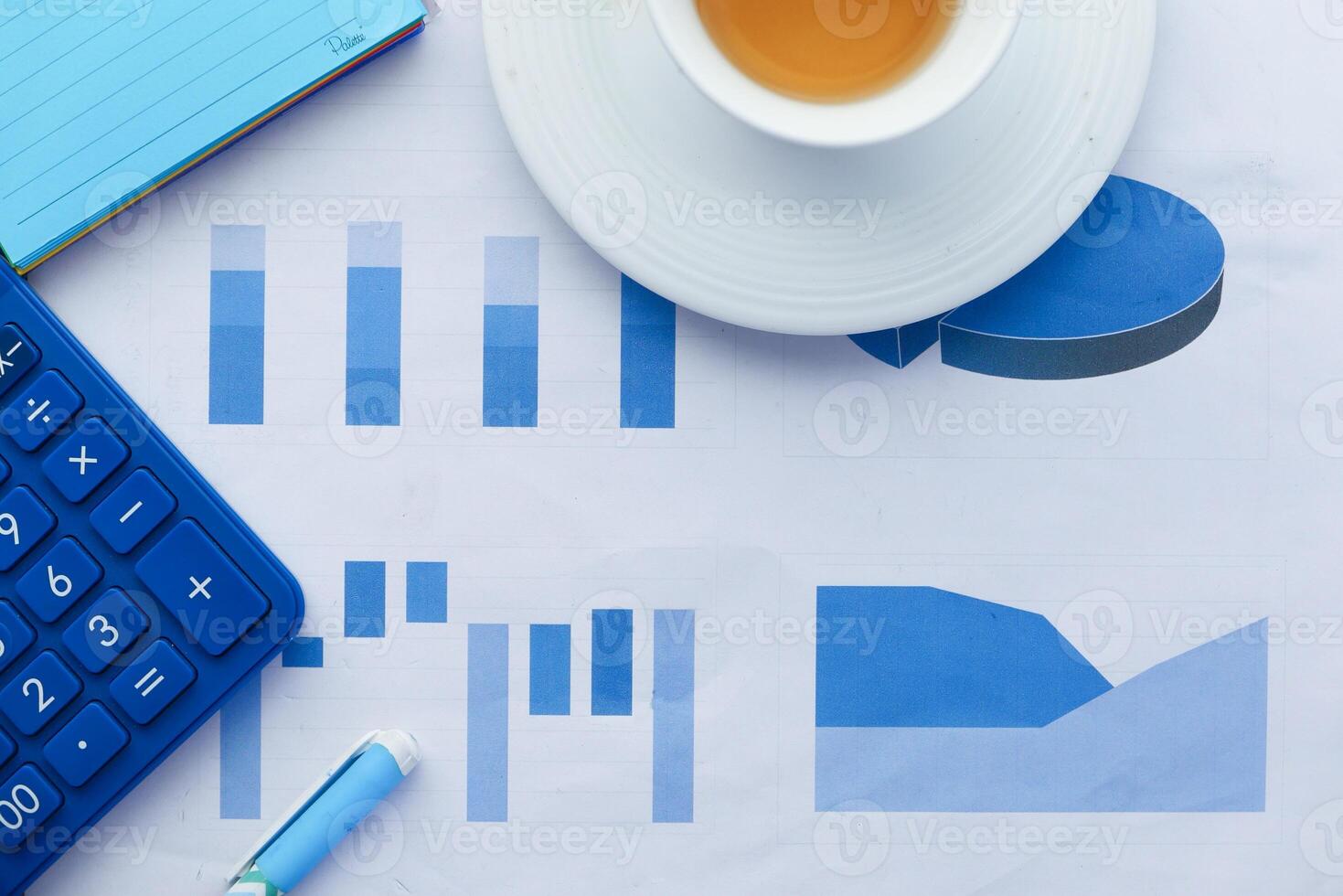 close up of financial charts, calculator and tea on table photo