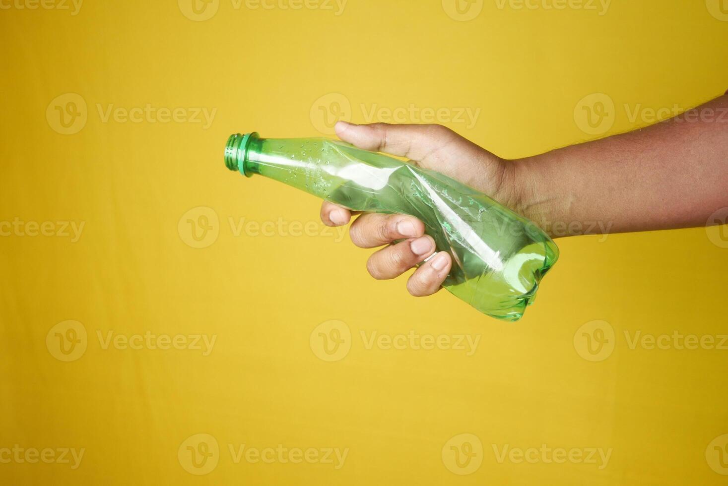 A person is grasping a plastic bottle with their fingers and thumb photo
