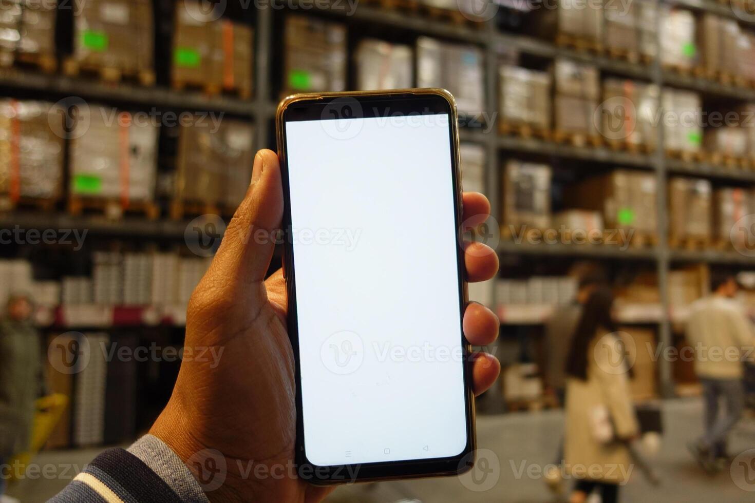 business owner holding phone mock up in warehouse. photo