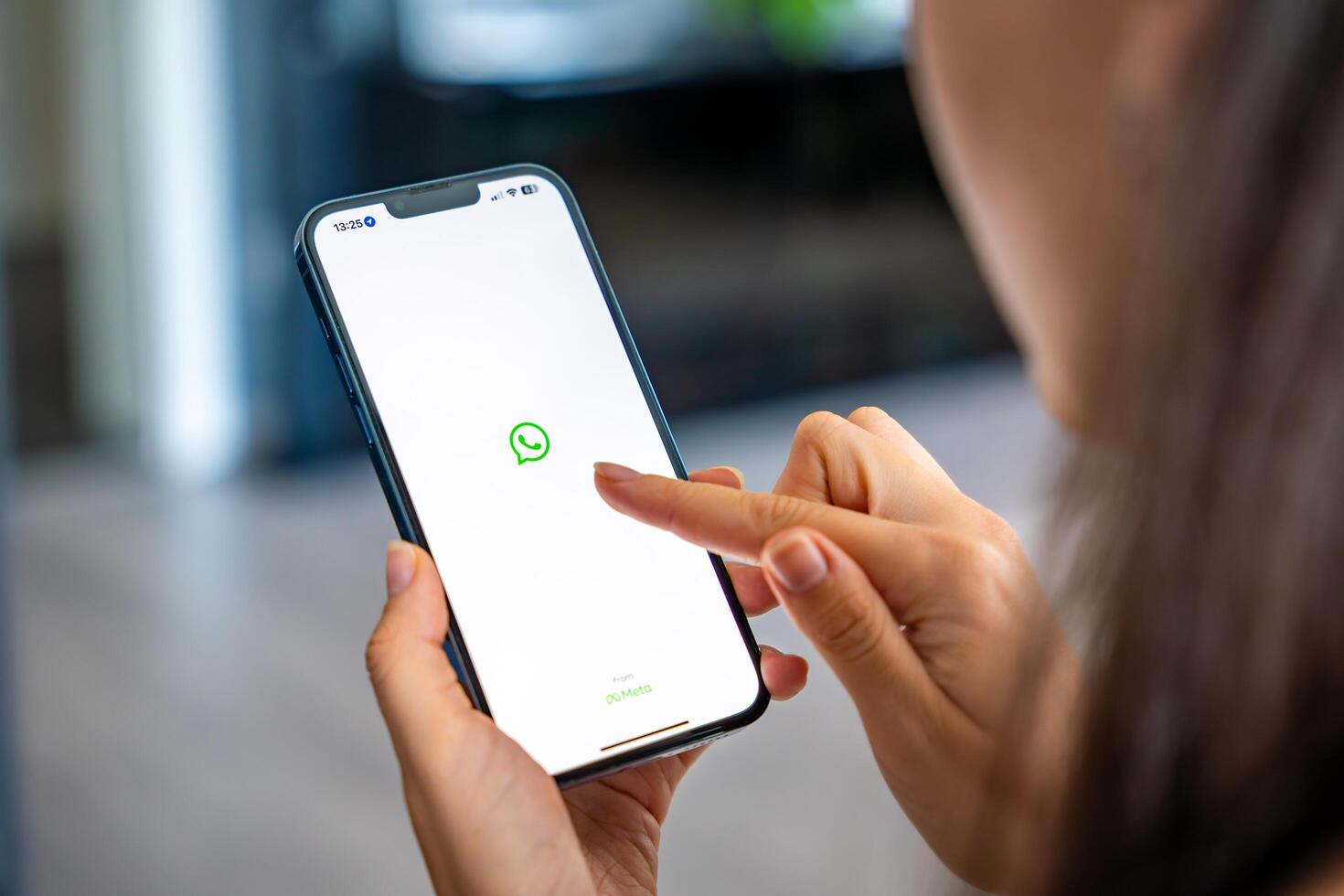 Prague, Czech republic - May 2, 2024. Woman holding iPhone with chat application WhatsApp on the screen, using mobile application for business home. High quality photo