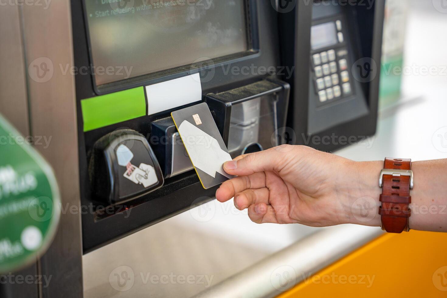 Close up view of man hand pays for fuel with a credit card on terminal of self-service filling station in Europe photo