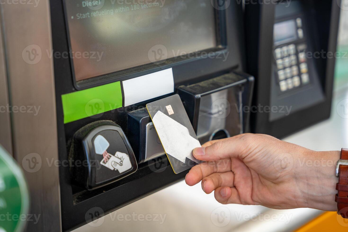 Close up view of man hand pays for fuel with a credit card on terminal of self-service filling station in Europe. High quality photo