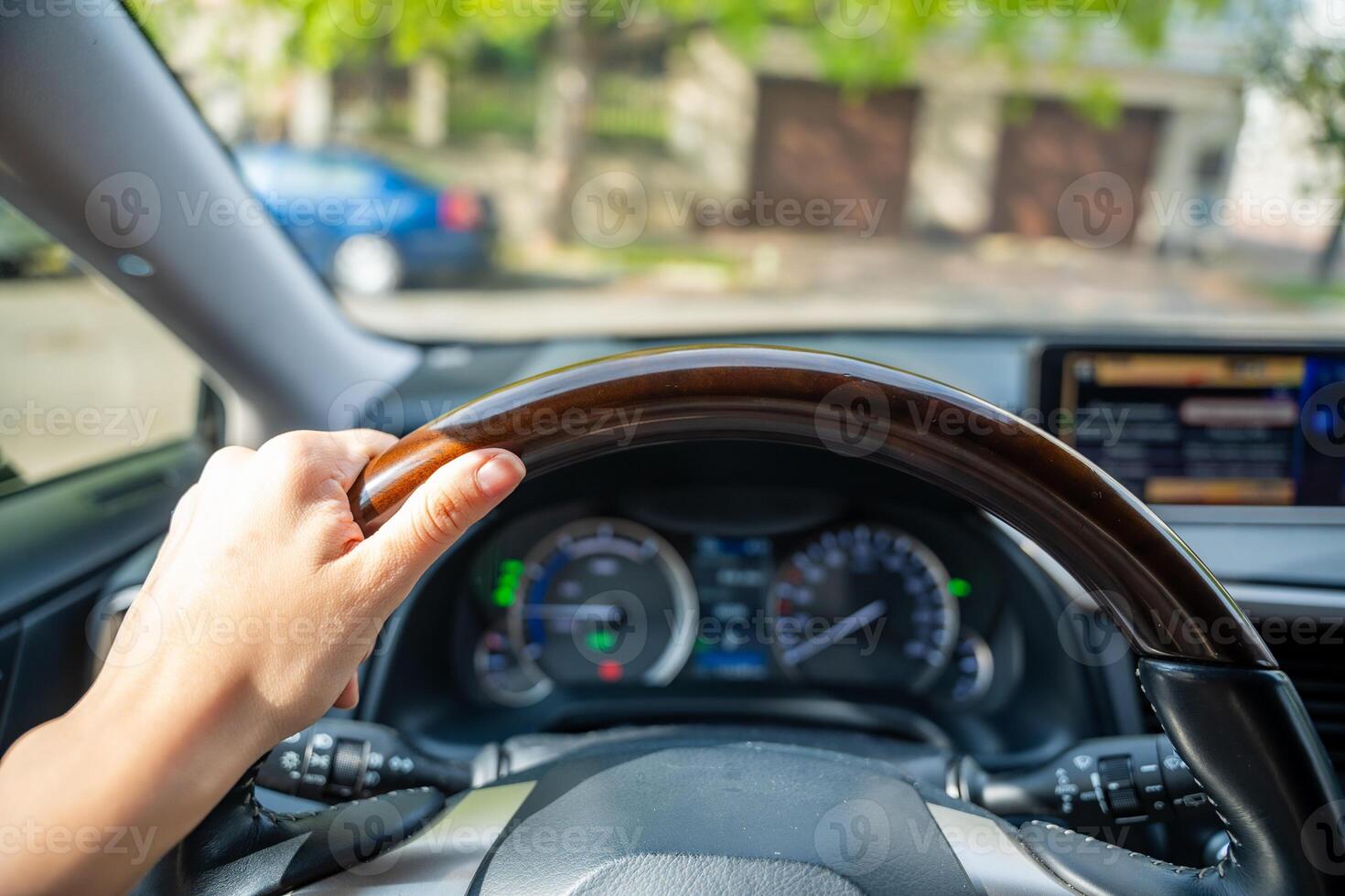 View of a woman's hand on the steering wheel of a car while driving in the city photo