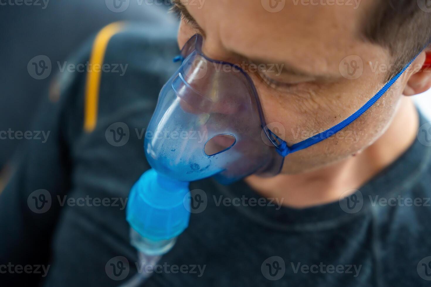 Unhealthy man wearing nebulizer mask in home. Health, medical equipment and people concept. High quality photo
