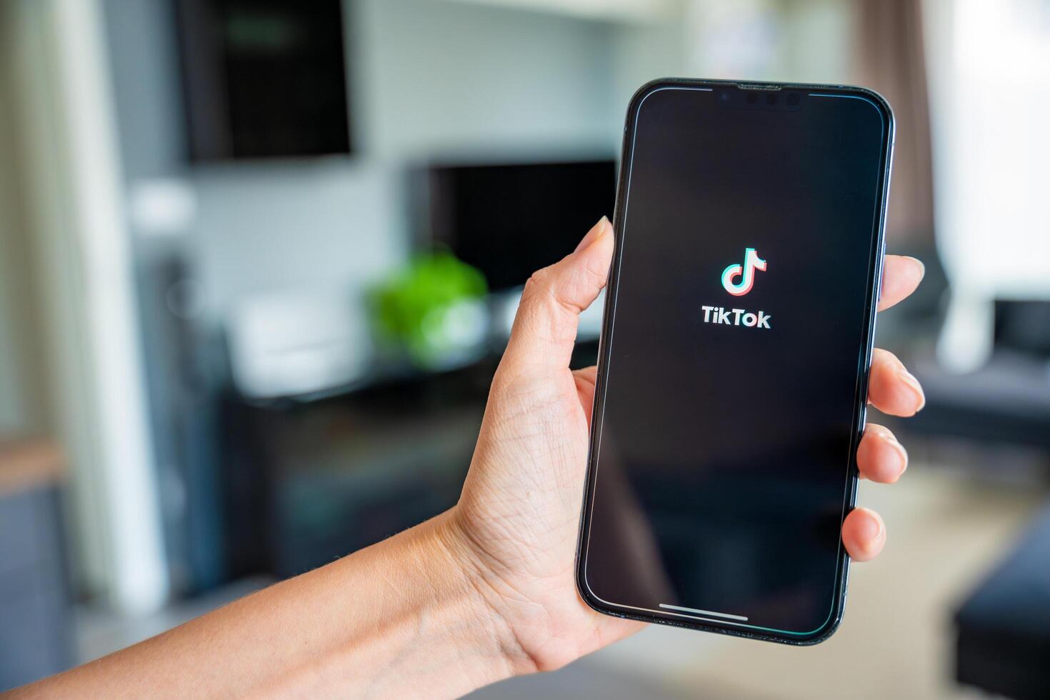 Prague, Czech republic - May 2, 2024. Woman holding iPhone with streaming service media and TikTok on the screen, using mobile application at home. High quality photo