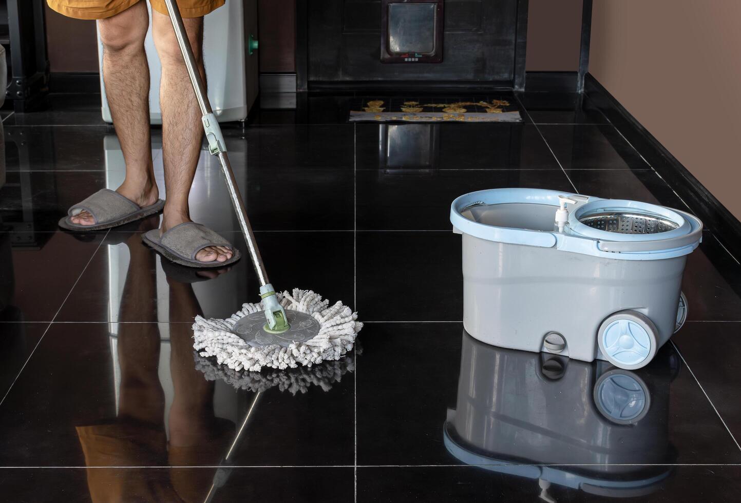 Man mopping floor and mopping bucket on the floor photo
