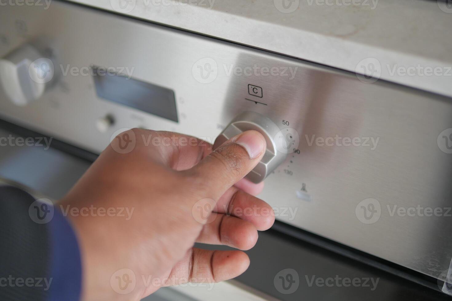 Close up of men hand setting temperature control on oven. photo
