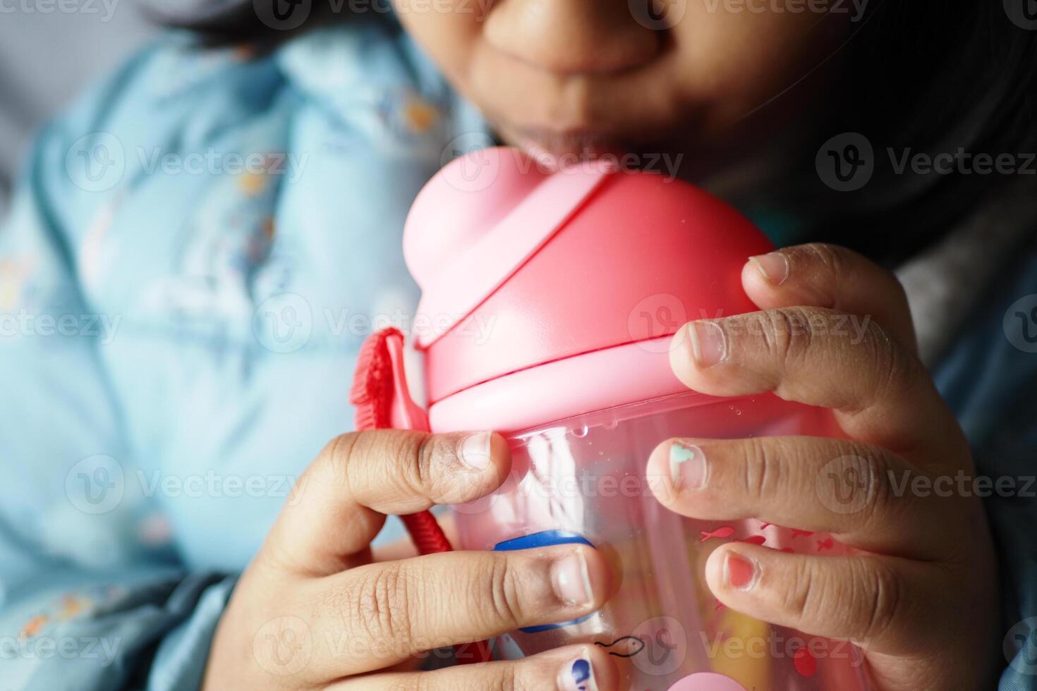 child girl drinking water sitting on sofa photo