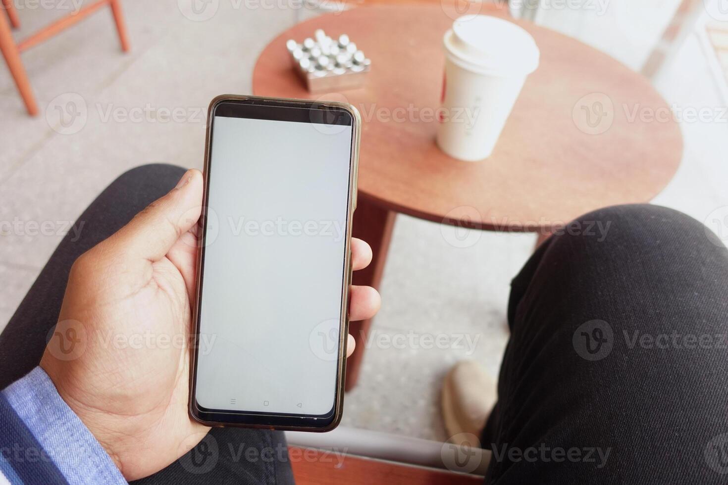 pov shot or young man hand using smart phone sitting on cafe photo