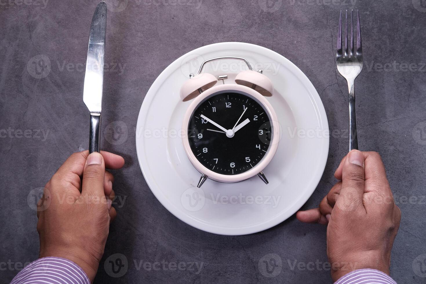 Alarm clock on plate on wooden table, top view. photo