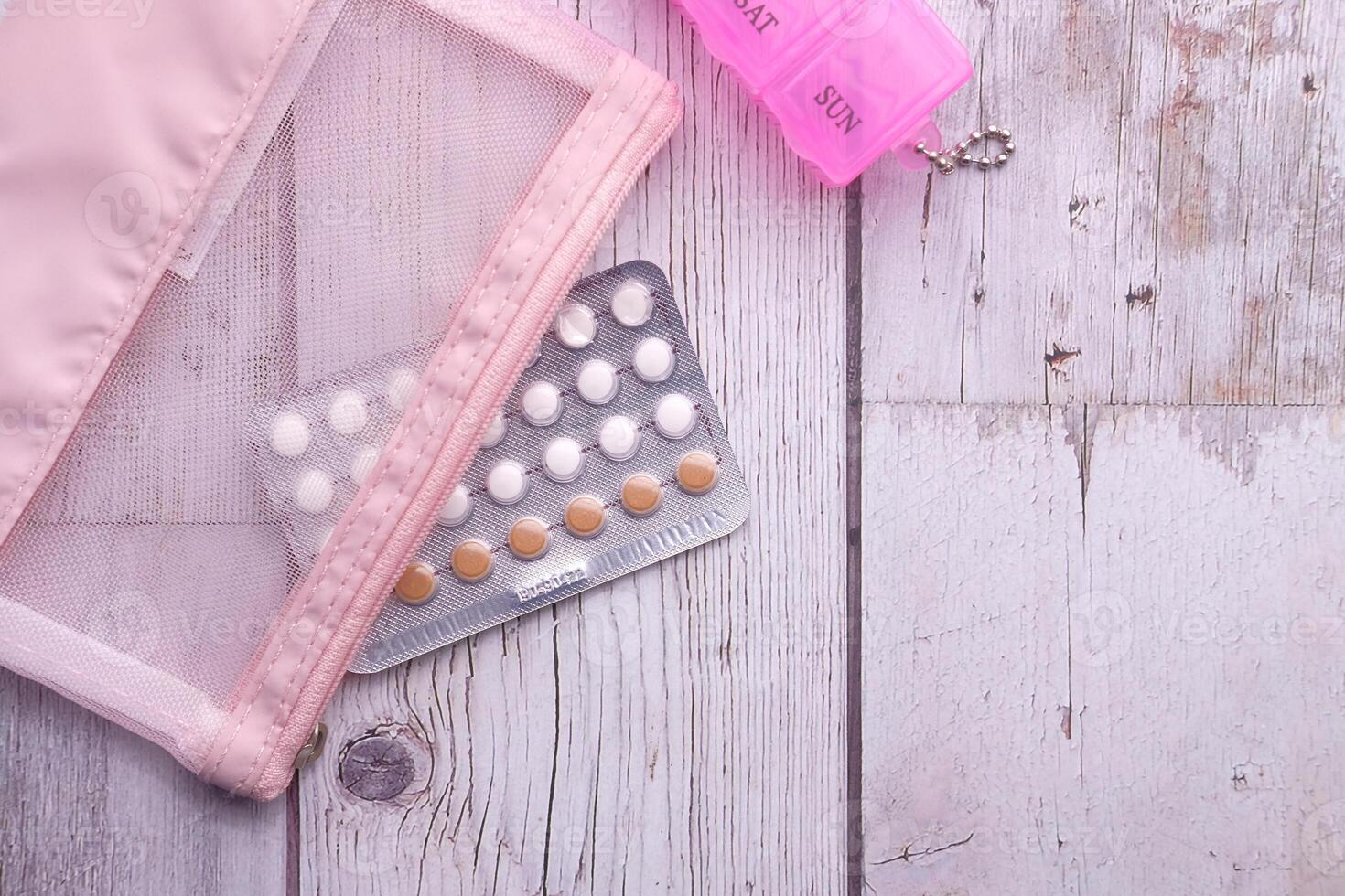 birth control pills and pill box on wooden table photo