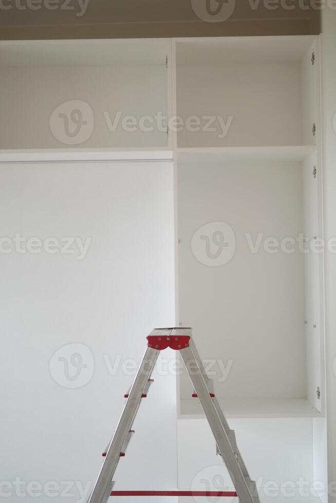 Metal ladder standing in empty room, renovation and improvement concept. photo