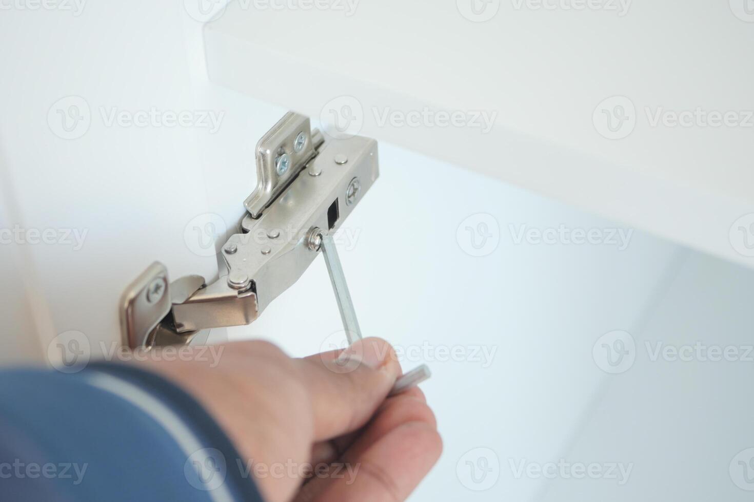 Using a wrench, theyre removing a screw from metal photo