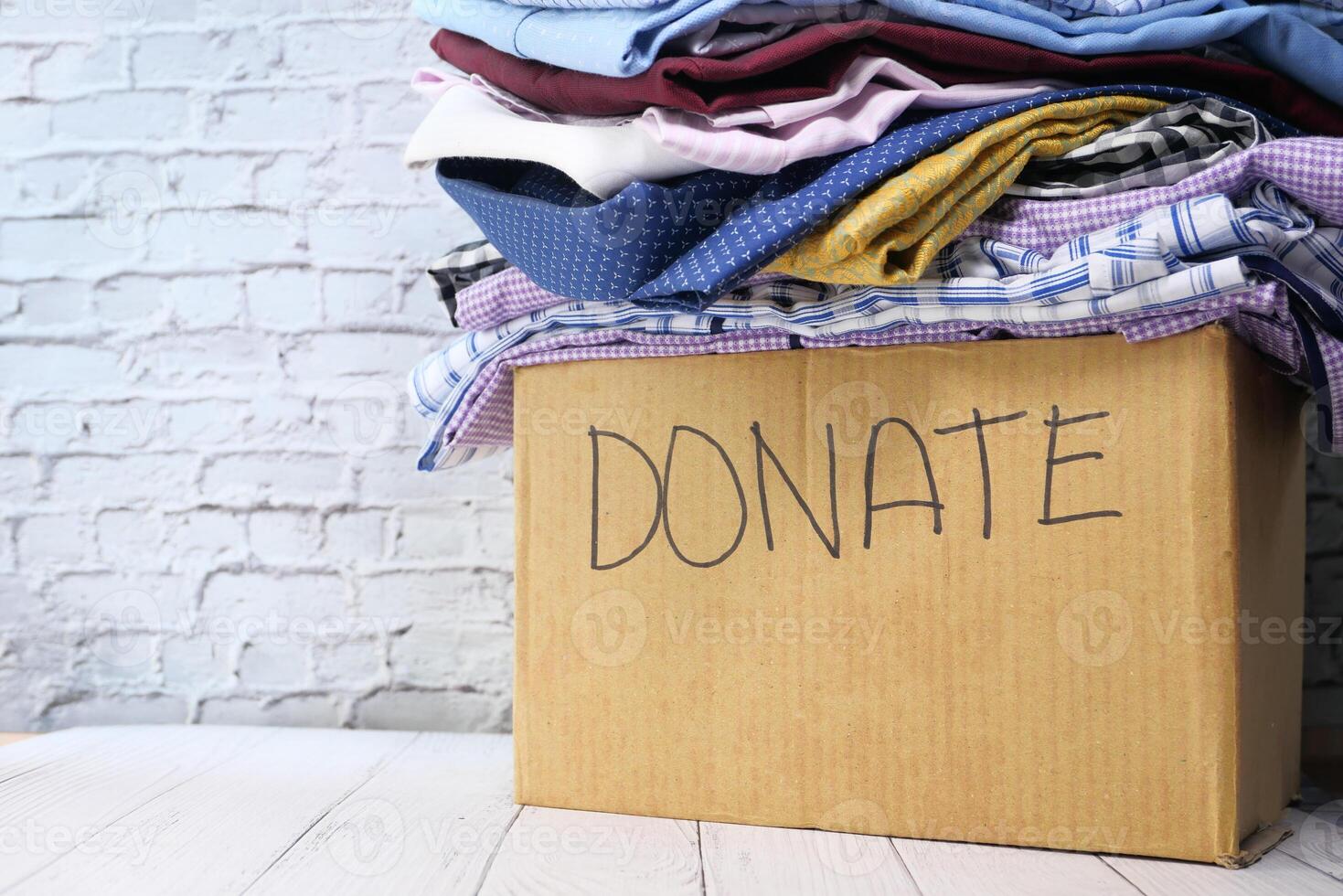Donation box with donation clothes on a wooden table . photo