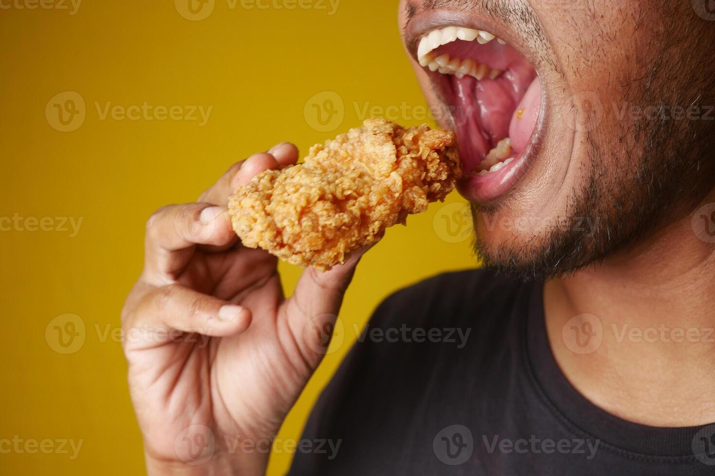 Man enjoying fried chicken, mouth open, savoring every bite with a big smile photo