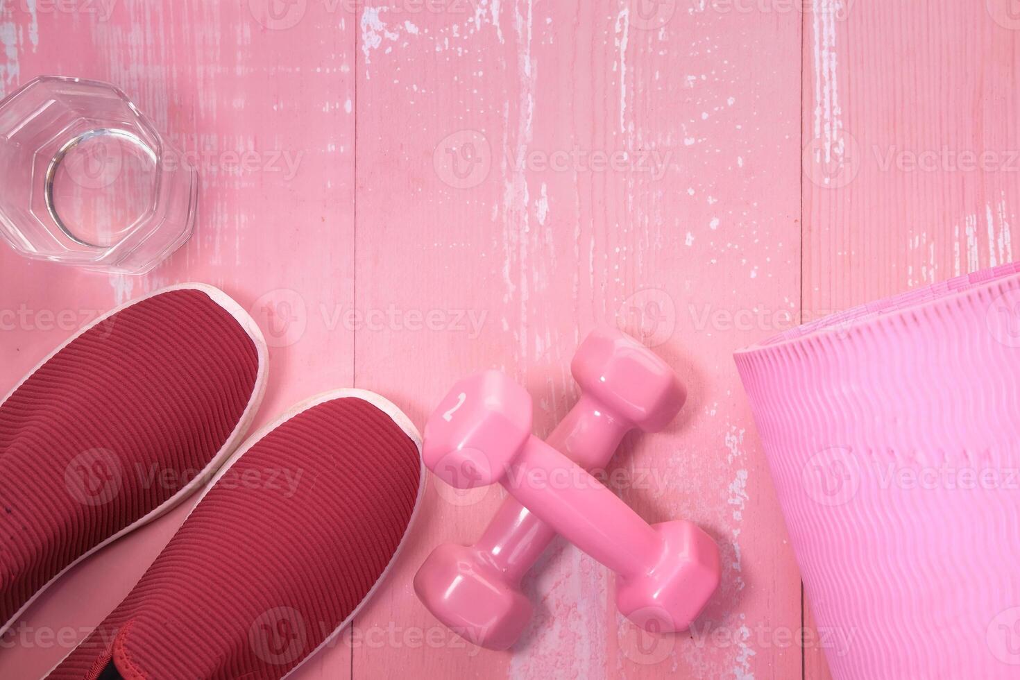 Close up of pink color dumbbell and glass of water on table photo