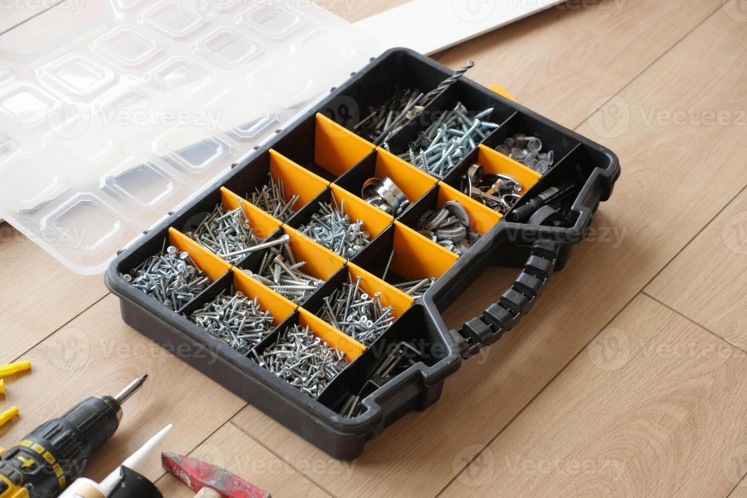 A wood flooring with a toolbox containing screws and drills photo