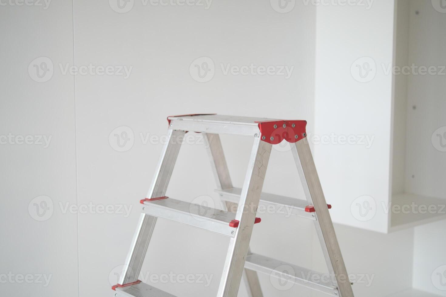 Metal ladder standing in empty room, renovation and improvement concept. photo