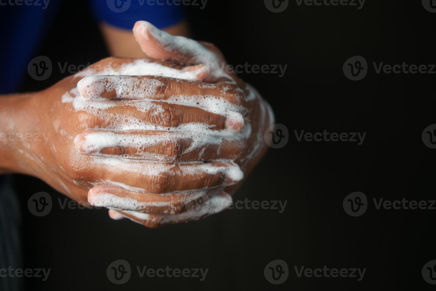 young man washing hands with soap warm water isolated on black background photo