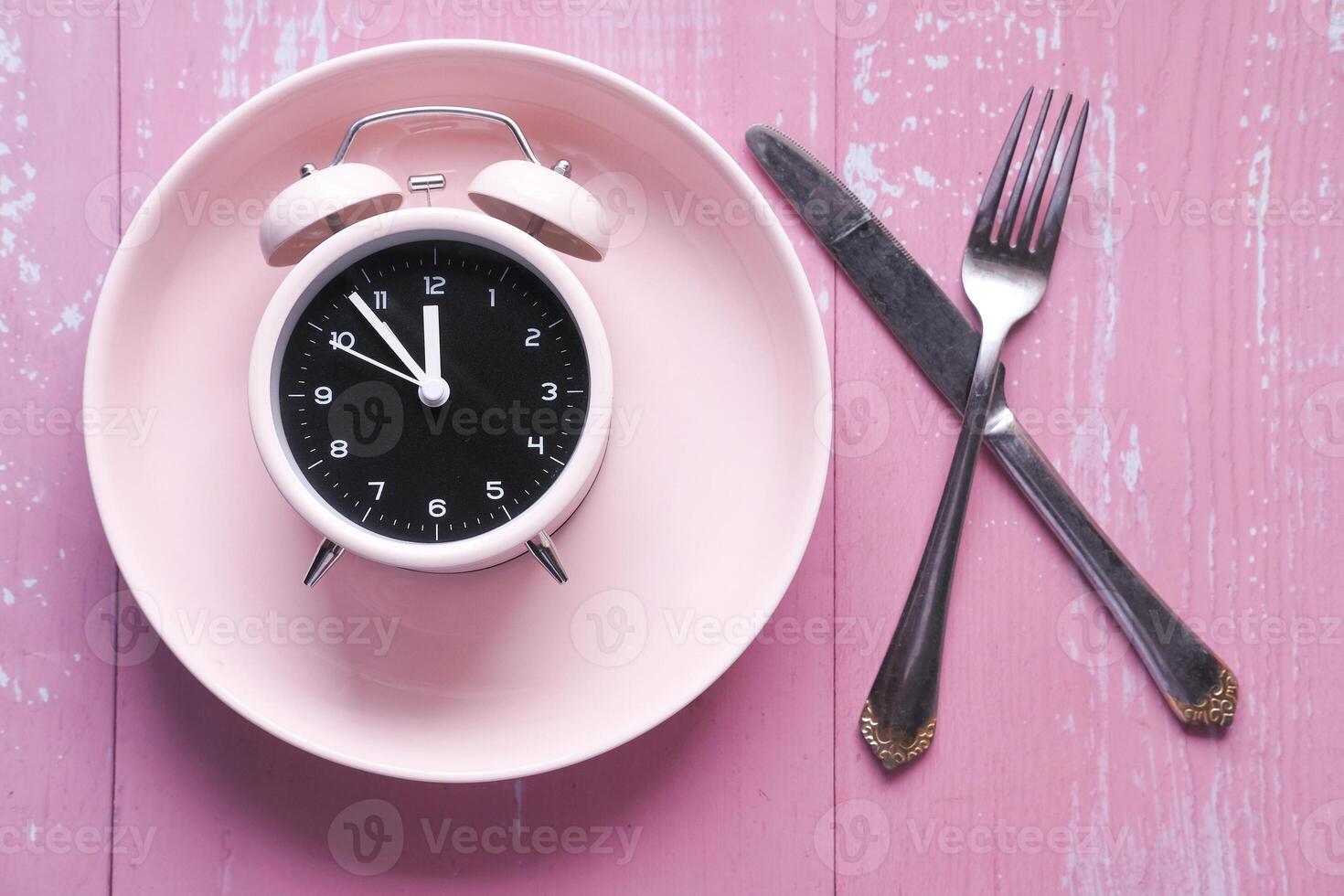 Alarm clock on plate on wooden table, top view. photo