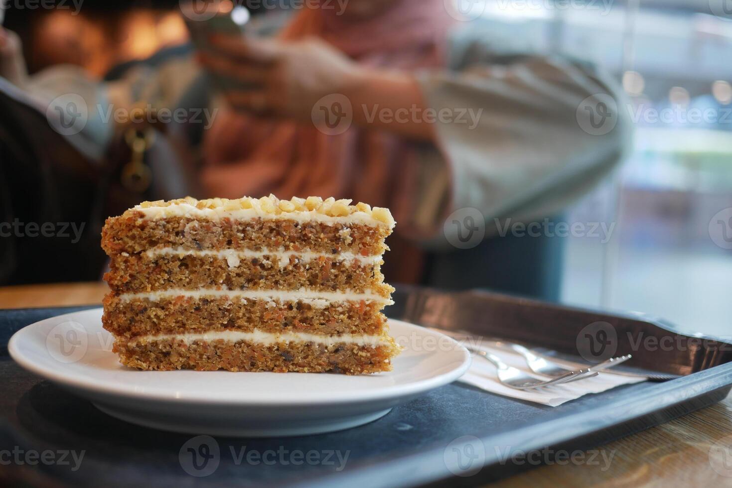 caramel cake on cafe table and a woman sitting on background photo