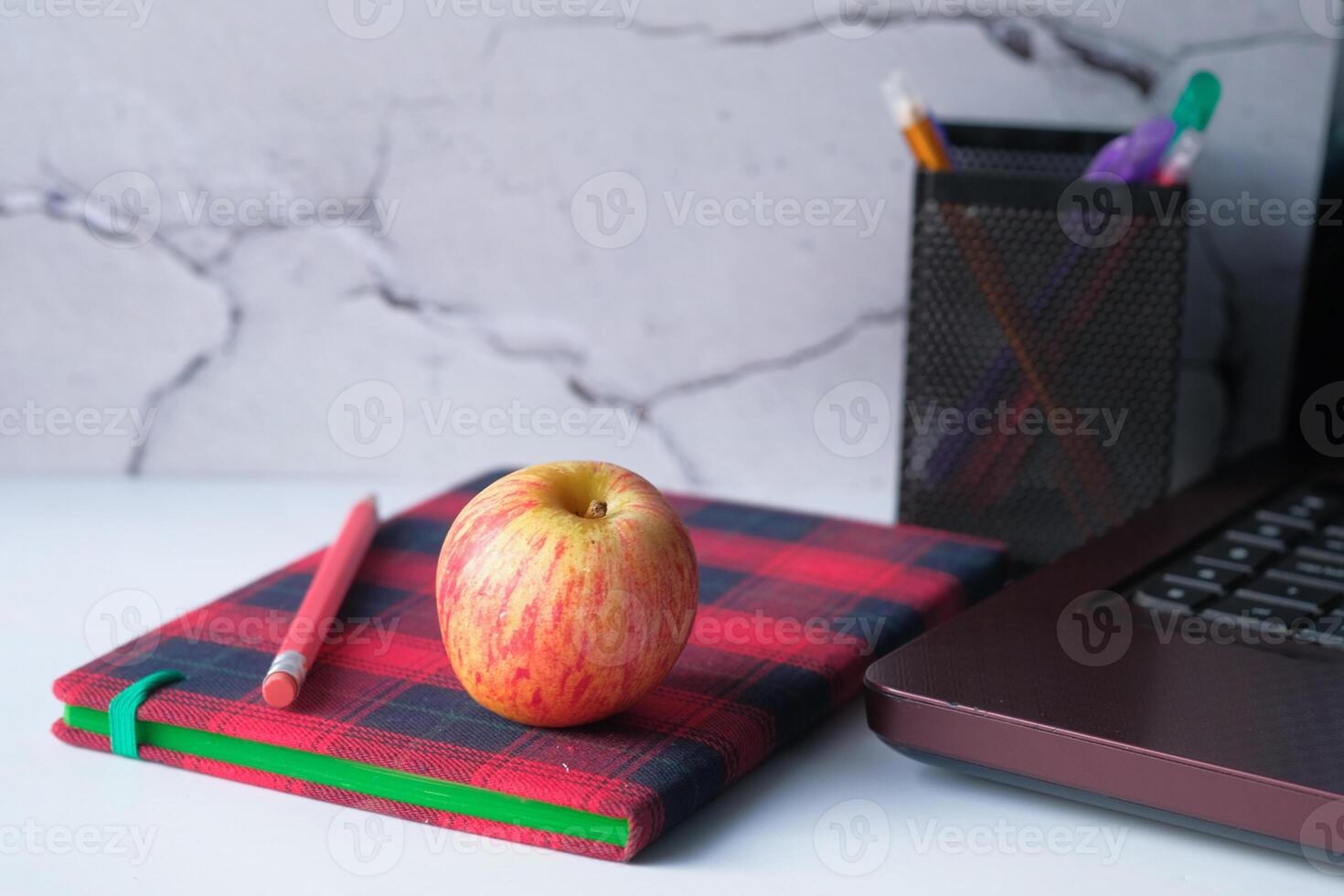 notebook with pencil and apple on table photo