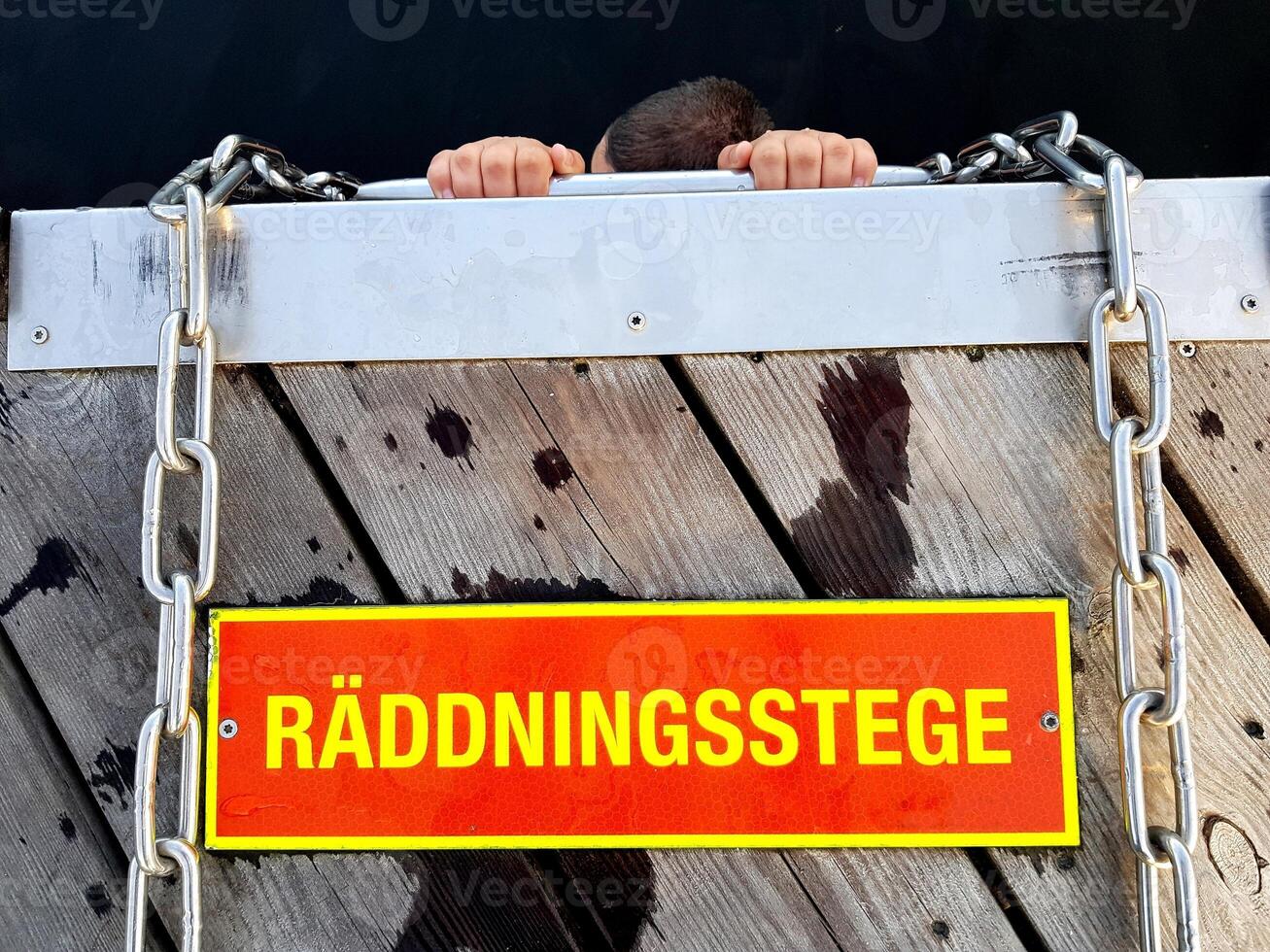A person clinging to a rescue ladder. On the sign nailed to the wood is written Rescue ladder. photo