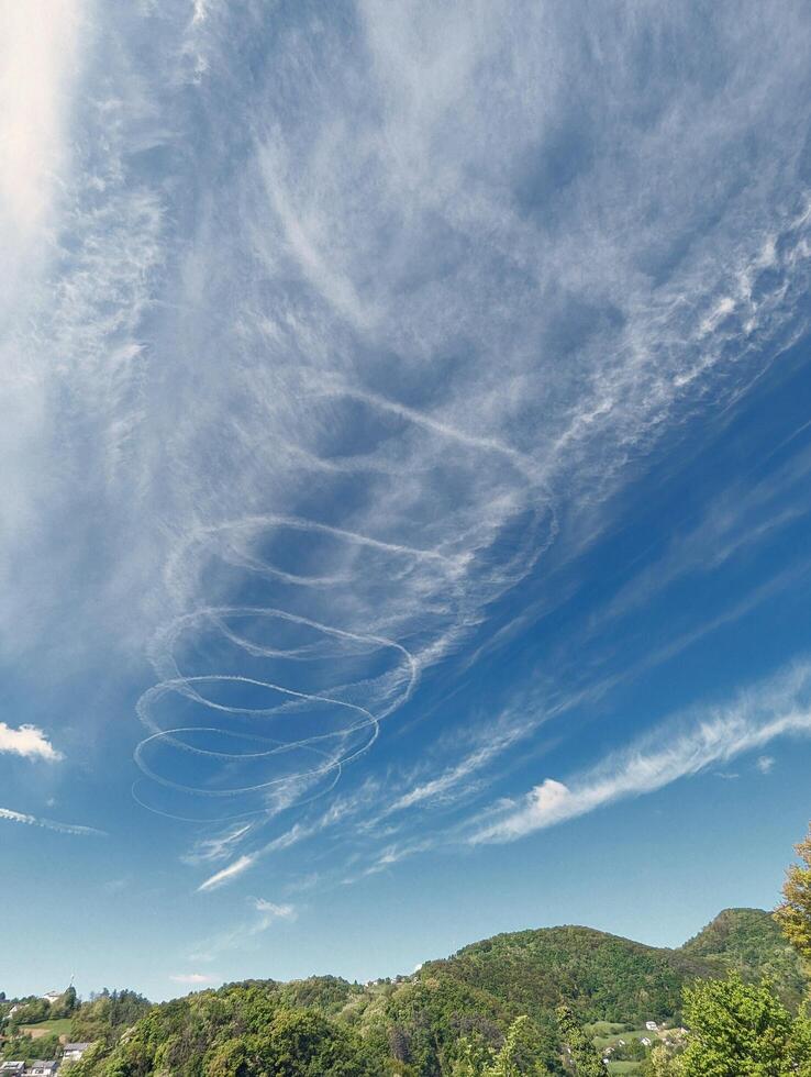 Blue sky with chemtrails from air plane, contrails, nature background, spiral shaped clouds photo