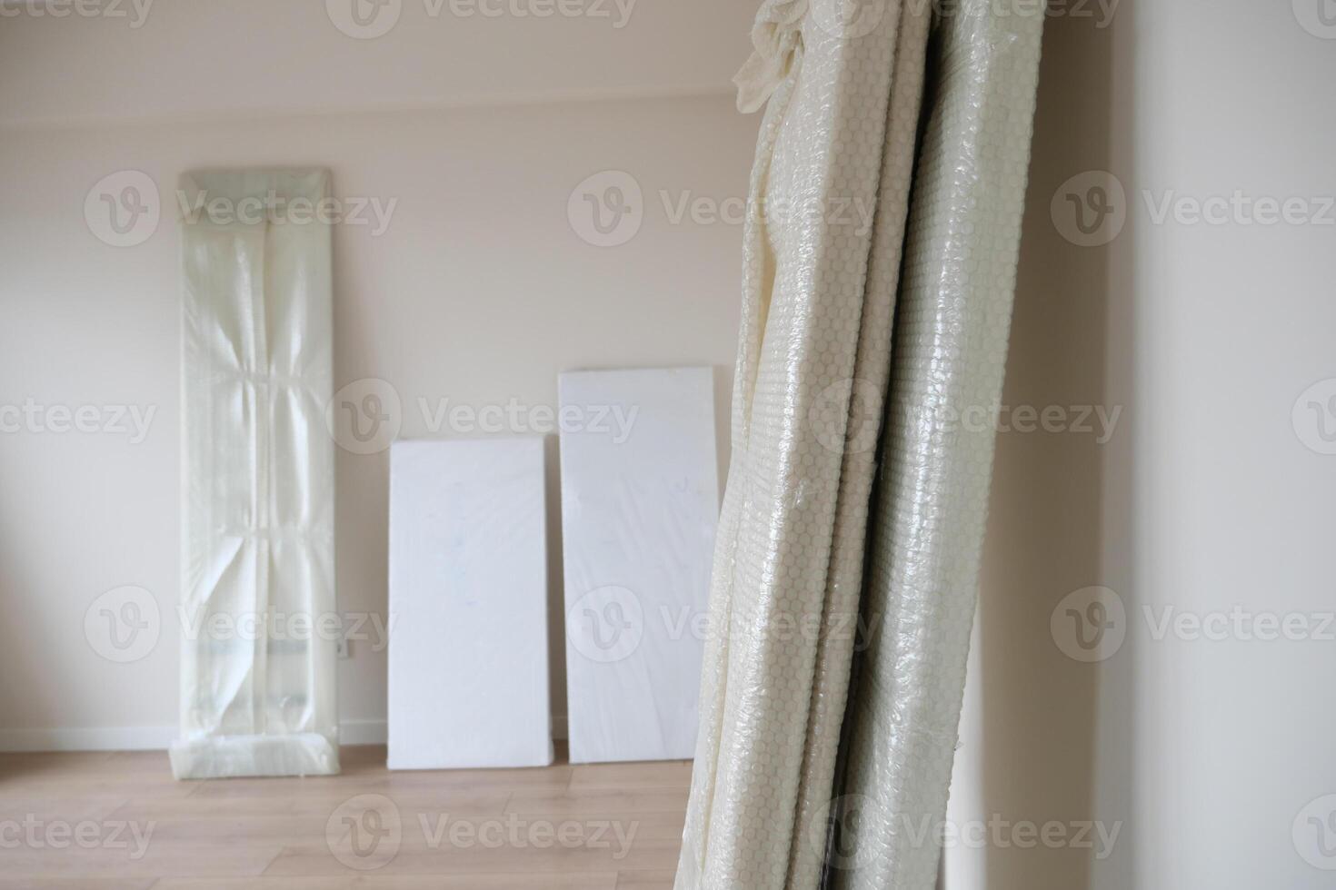 An empty room with hardwood flooring and wrapped in plastic. photo