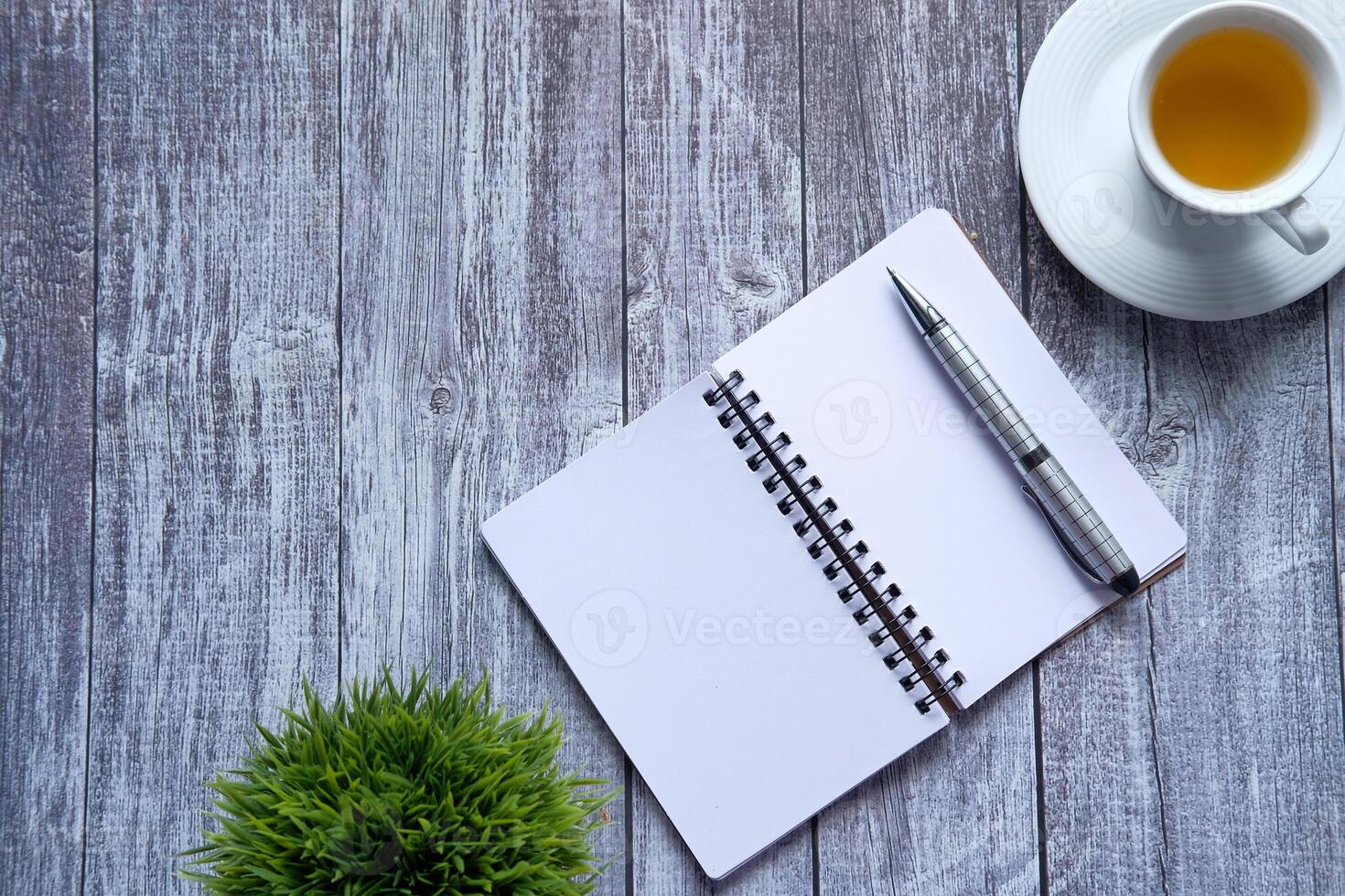 high angle view of open notepad, pen and tea on table photo