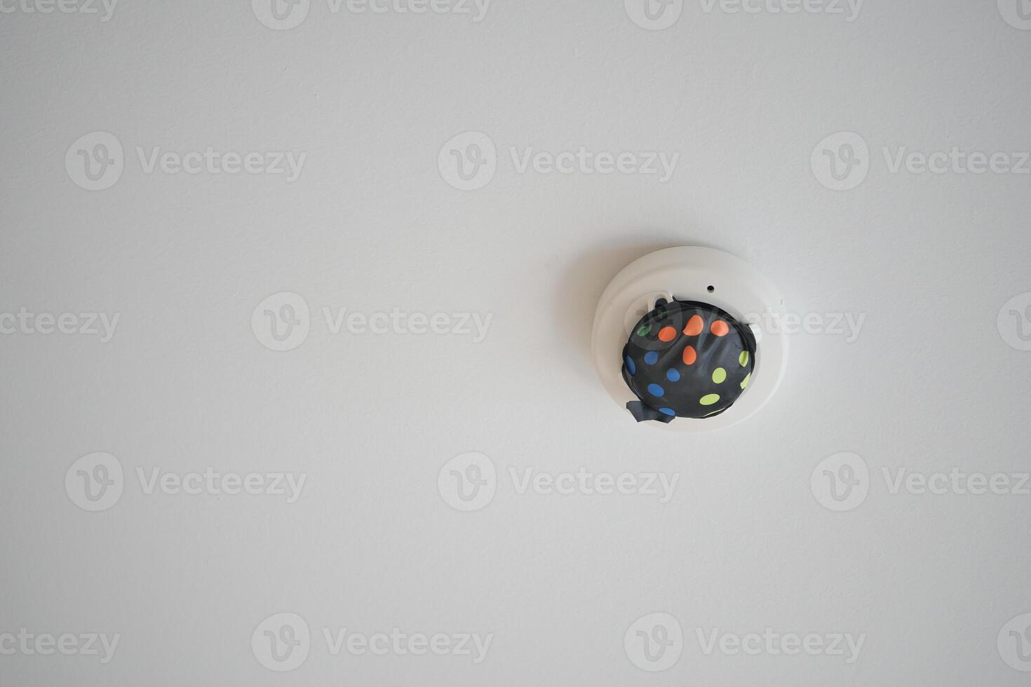 White smoke detector on ceiling at home photo