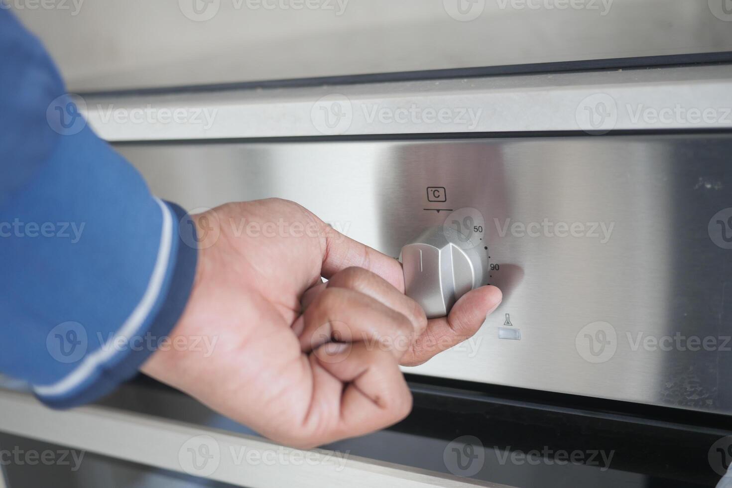 Close up of hand setting temperature control on electric oven. photo