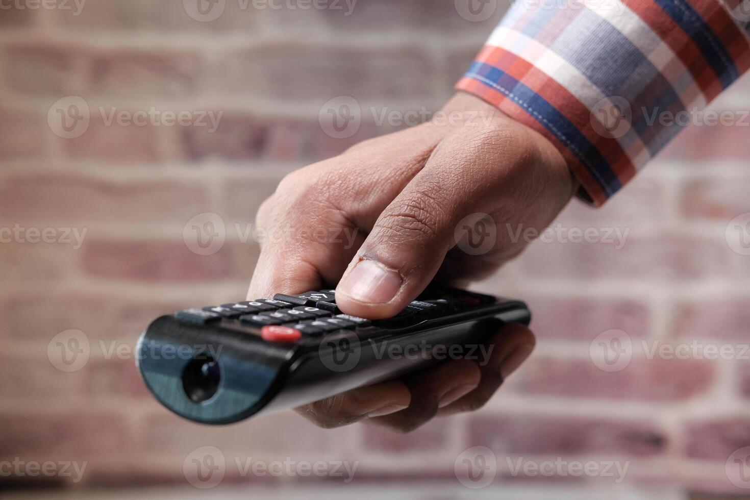 close up of man's hand using tv remote photo