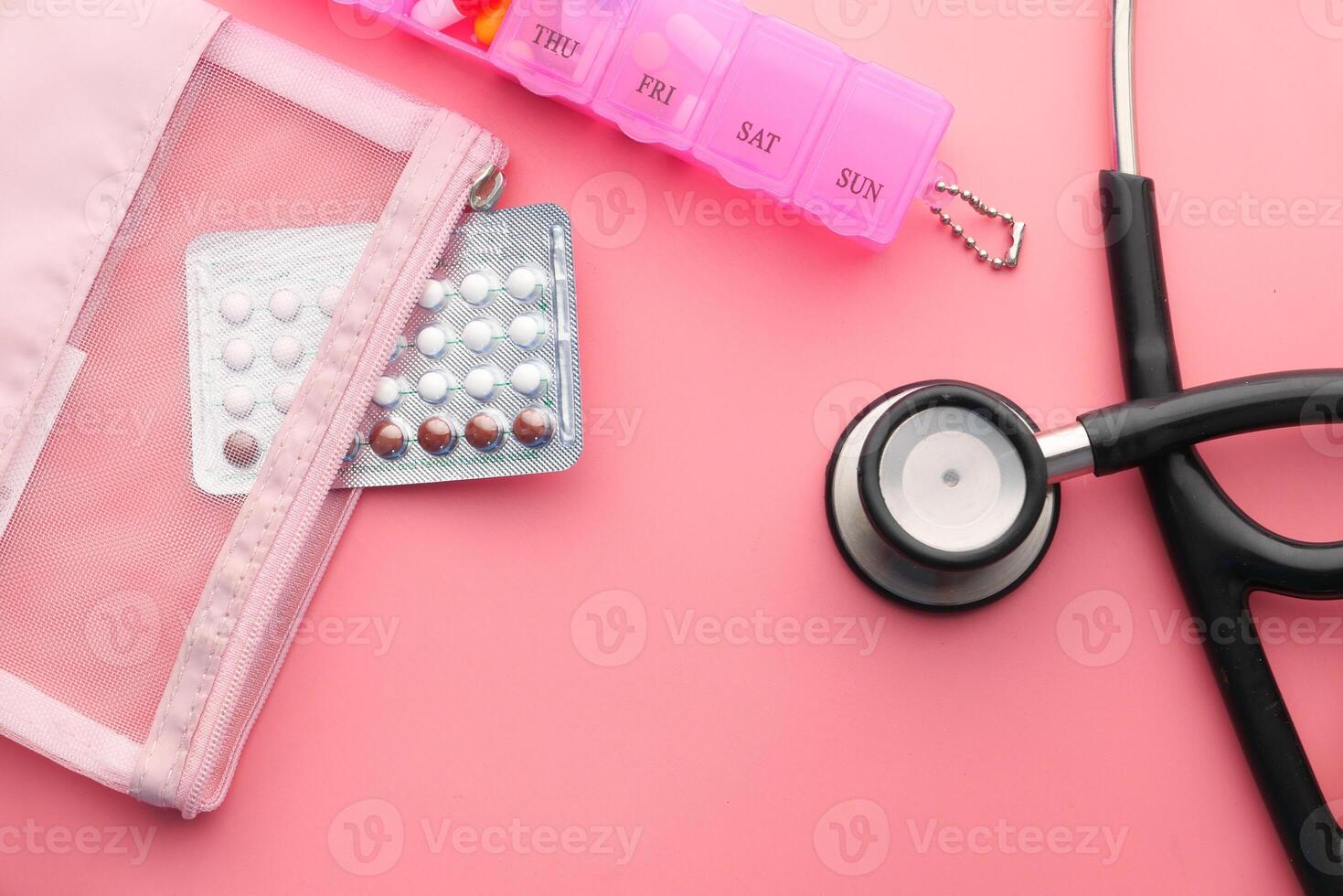 birth control pills and stethoscope on pink photo