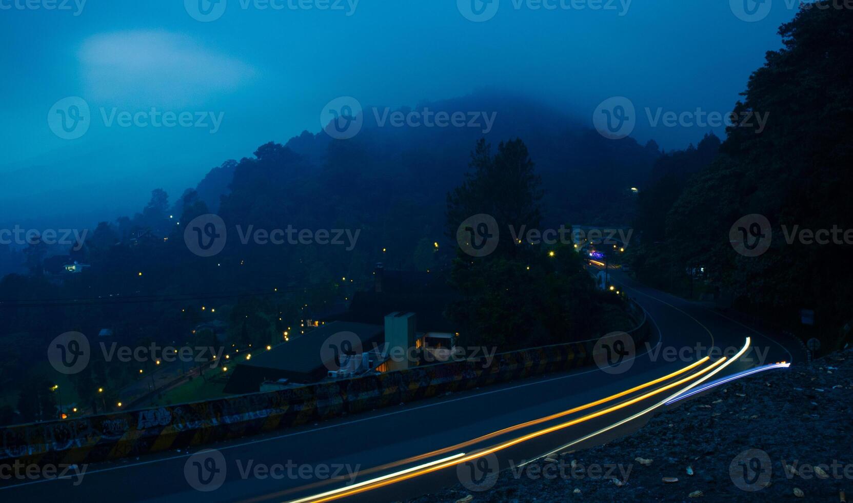 colorful night light trails on road with forest background in puncak bogor Indonesia photo
