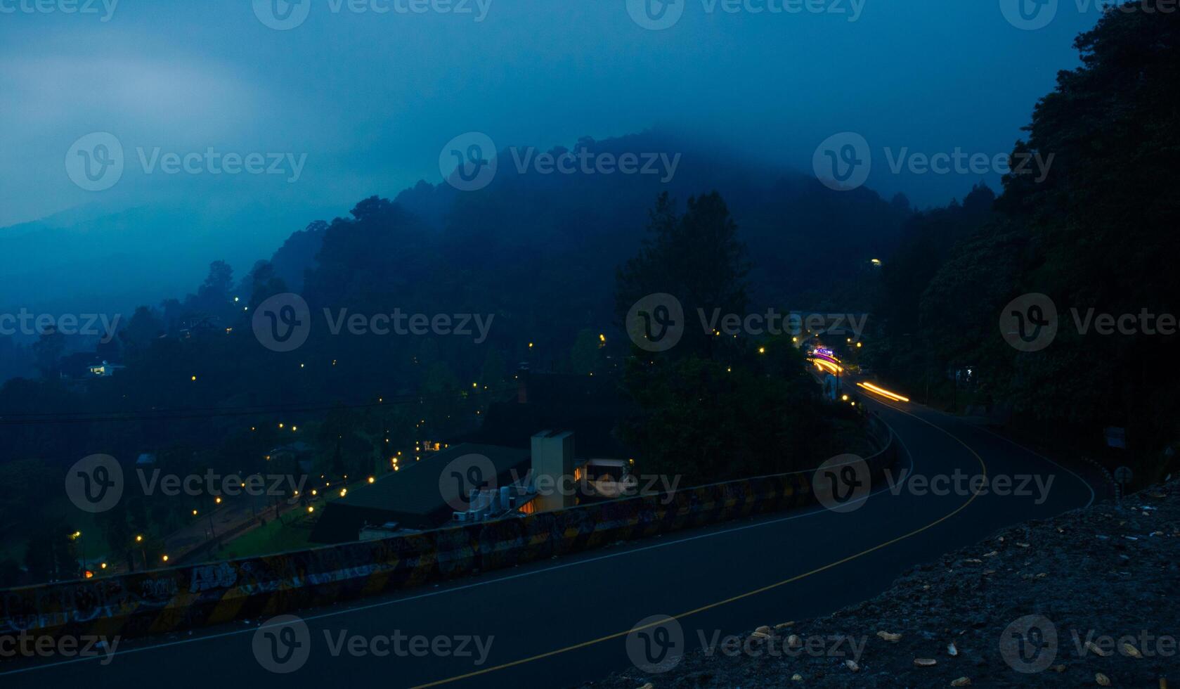 colorful night light trails on road with forest background in puncak bogor Indonesia photo