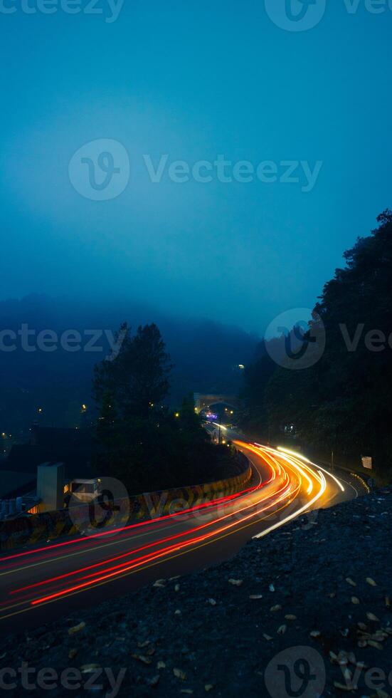 colorful night light trails on road with forest background in puncak bogor Indonesia photo