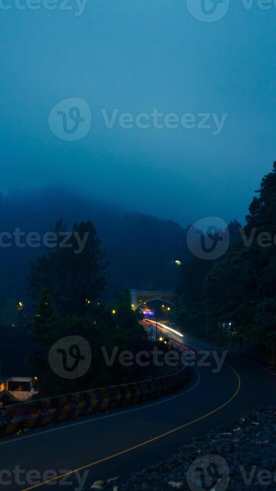 colorful night light trails on road with forest background in puncak bogor Indonesia photo