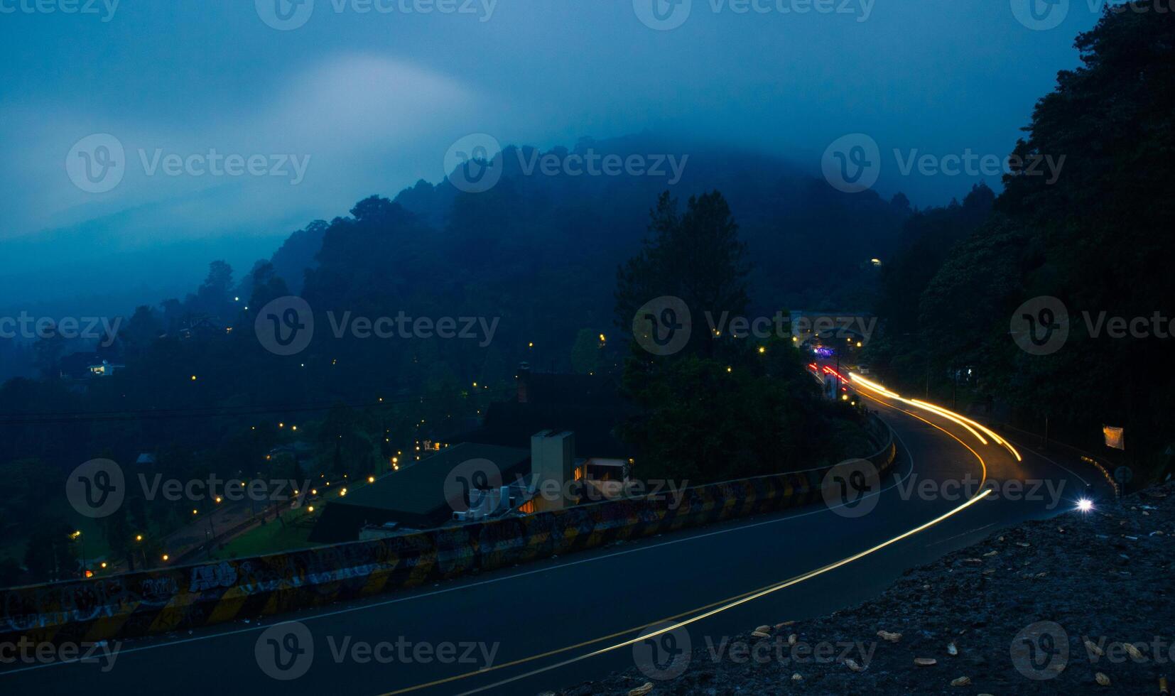 colorful night light trails on road with forest background in puncak bogor Indonesia photo