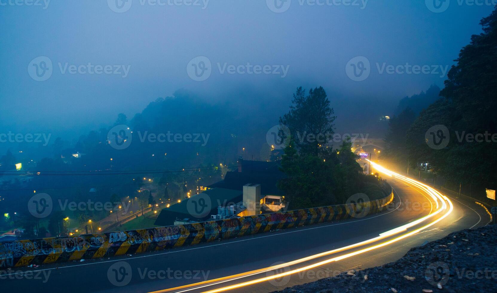 colorful night light trails on road with forest background in puncak bogor Indonesia photo