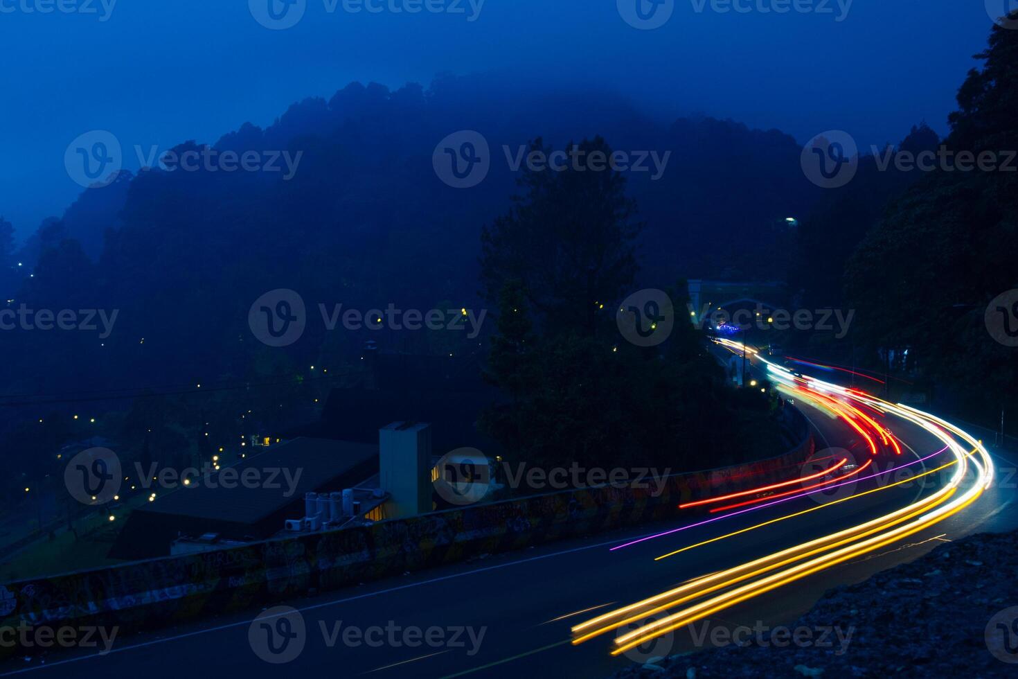 colorful night light trails on road with forest background in puncak bogor Indonesia photo