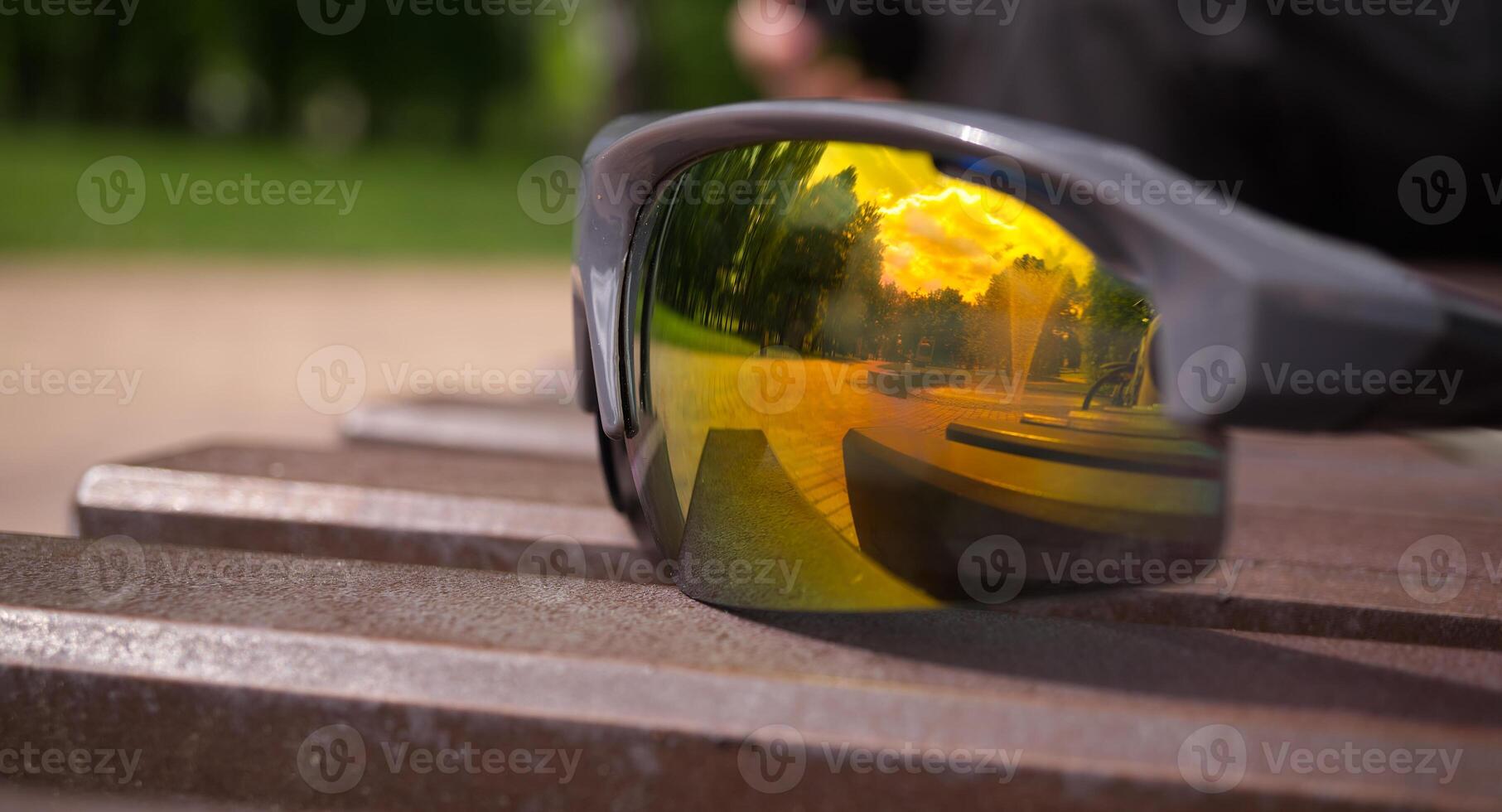 Sunglasses reflects sunset sky with hues of orange and yellow photo