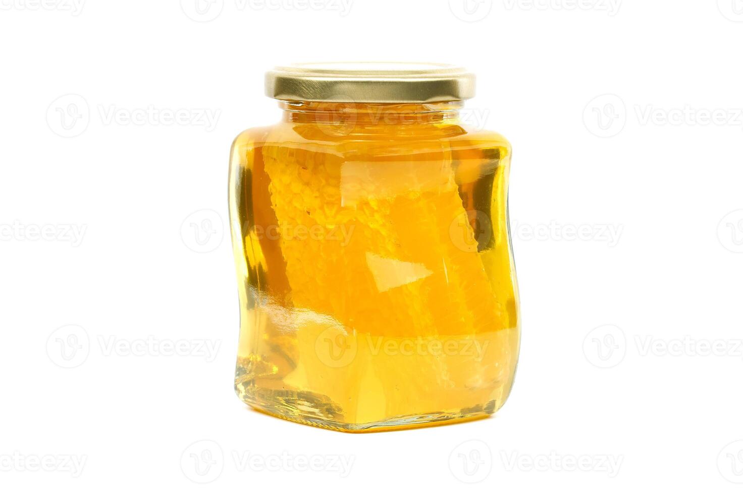 Glass jar filled with honey and honeycomb isolated on white photo