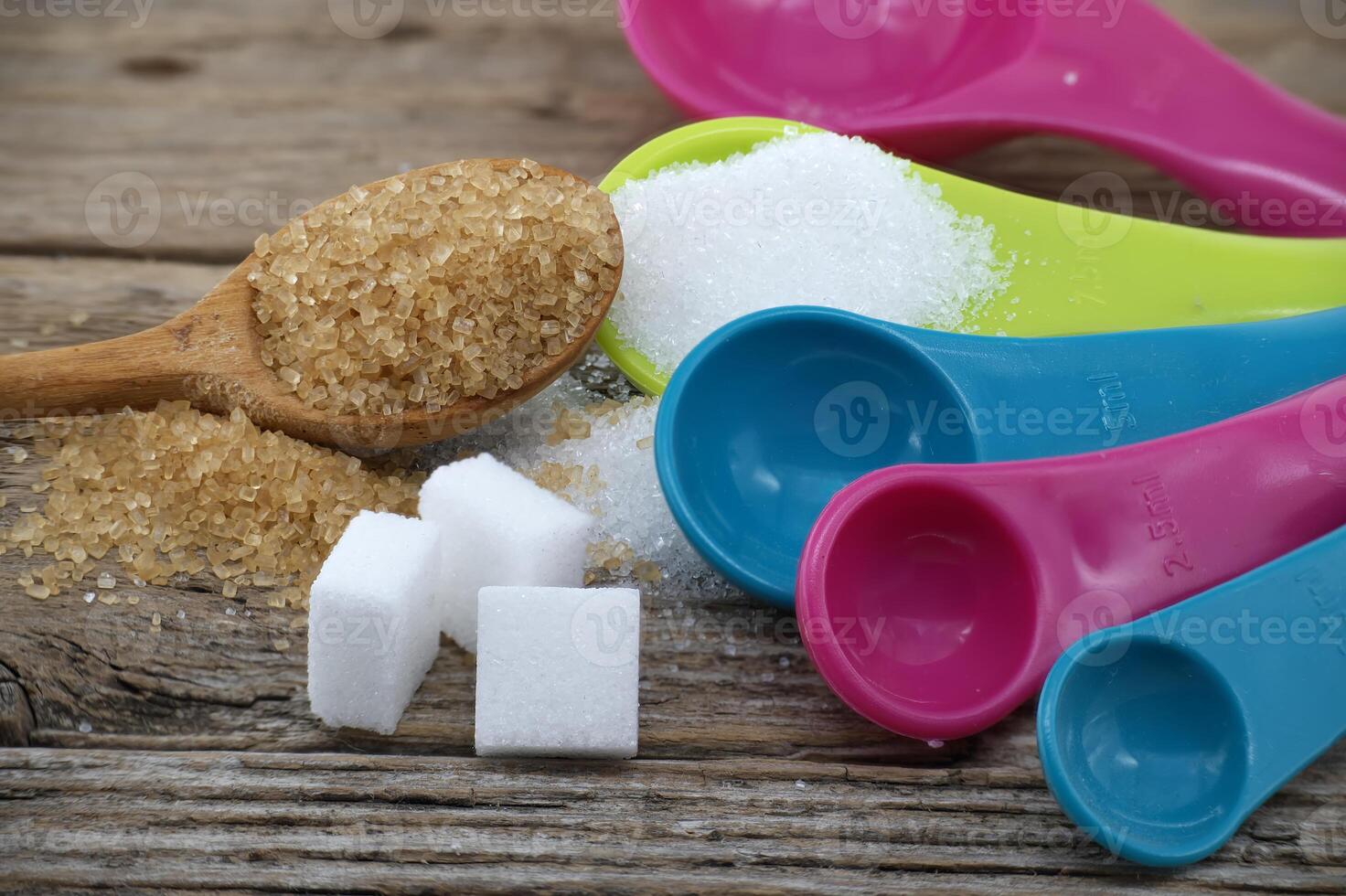 Measuring utensils and spilled sugar on rustic wood photo