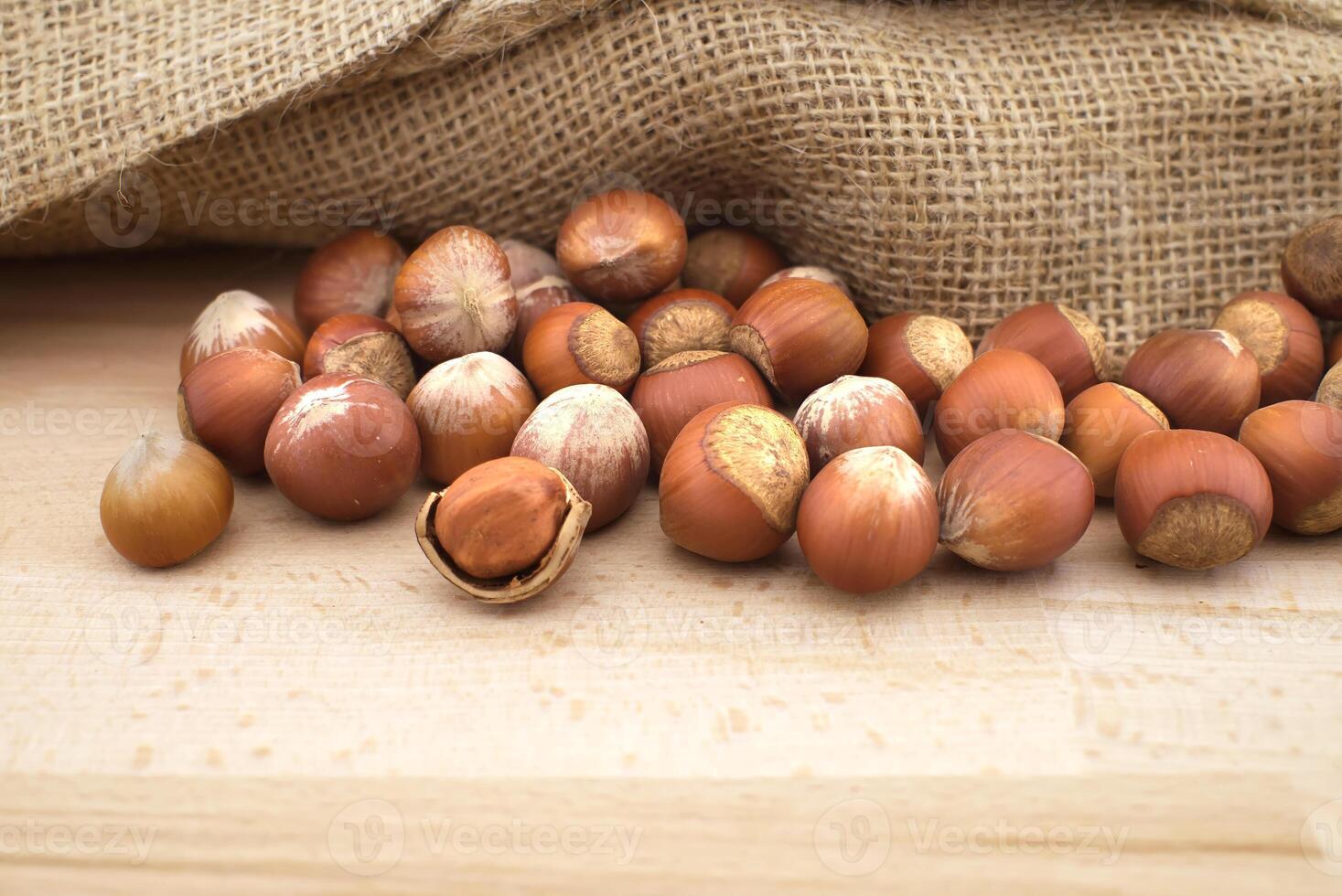 Hazelnuts beside the jute sack on wooden table photo
