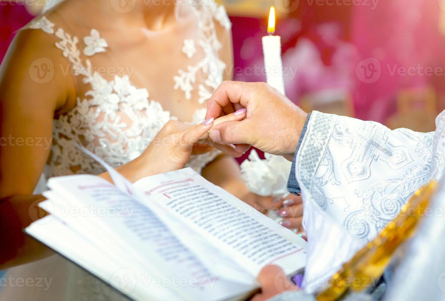 Newlyweds stand before the priest on a wedding ceremony and exchange the rings photo