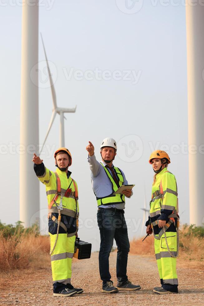 Specialist wind turbine Team of Engineers discussing Green Energy Production in Wind Turbines Farm or Windmills Field. Team of Engineer Energy Planning Activity in Windmills Industrial Area photo