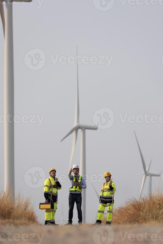 Specialist wind turbine Team of Engineers discussing Green Energy Production in Wind Turbines Farm or Windmills Field. Team of Engineer Energy Planning Activity in Windmills Industrial Area photo